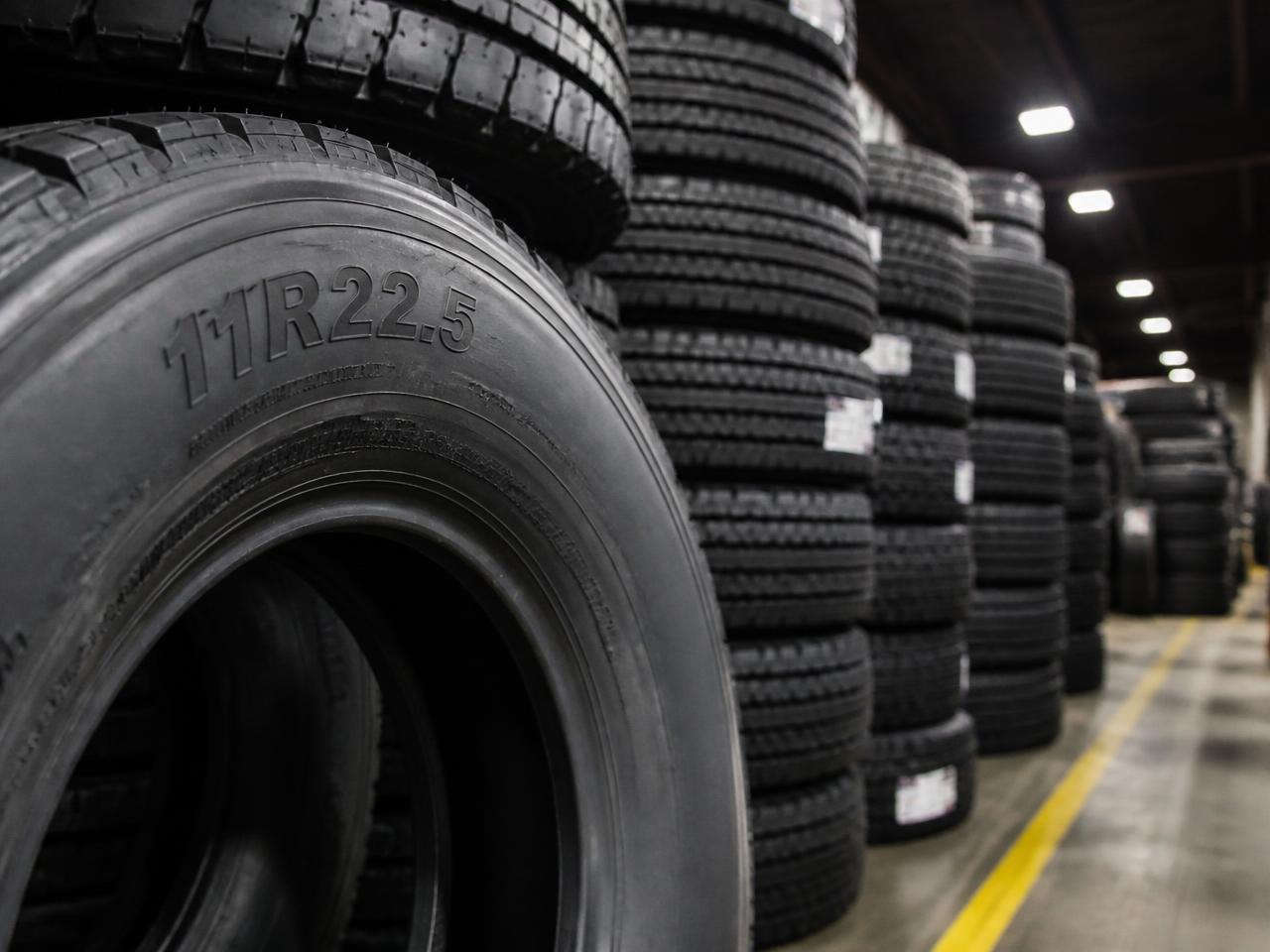 Stacks of 11R22.5 semi truck tires in a commercial tire warehouse